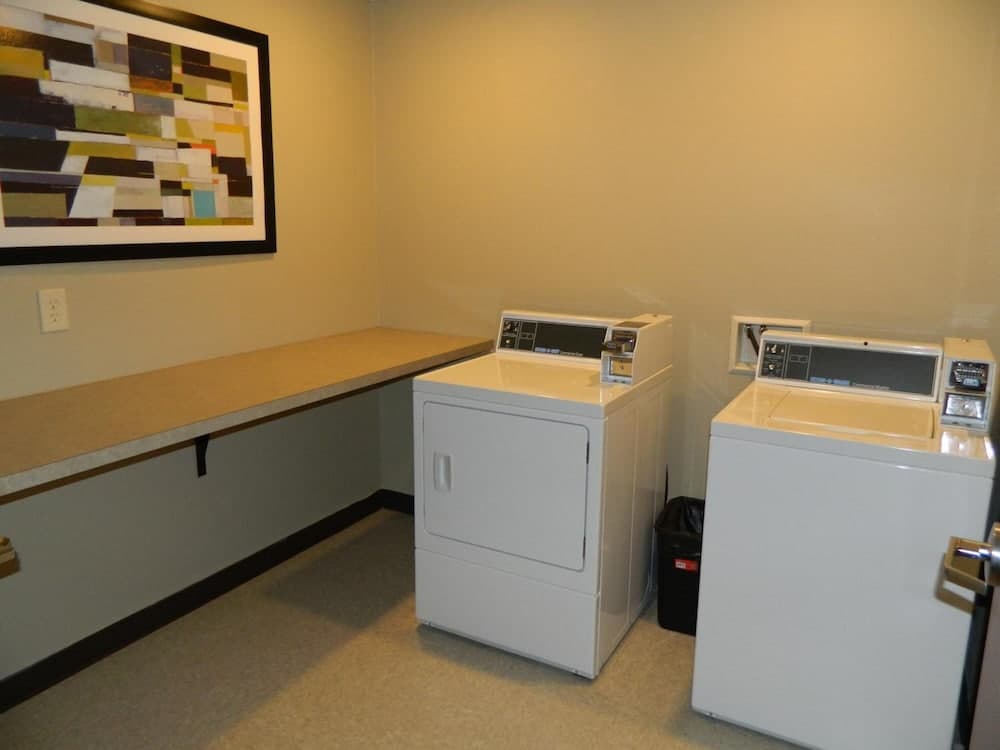 A cozy laundry room with white appliances, a countertop, and abstract wall art offers a practical space for travelers needing to wash clothes during their stay.