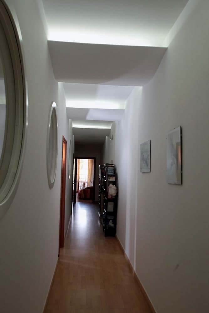 A serene indoor hallway with modern lighting, wooden flooring, framed artwork, and a cozy bedroom at the end, ideal for travelers seeking a tranquil accommodation experience.