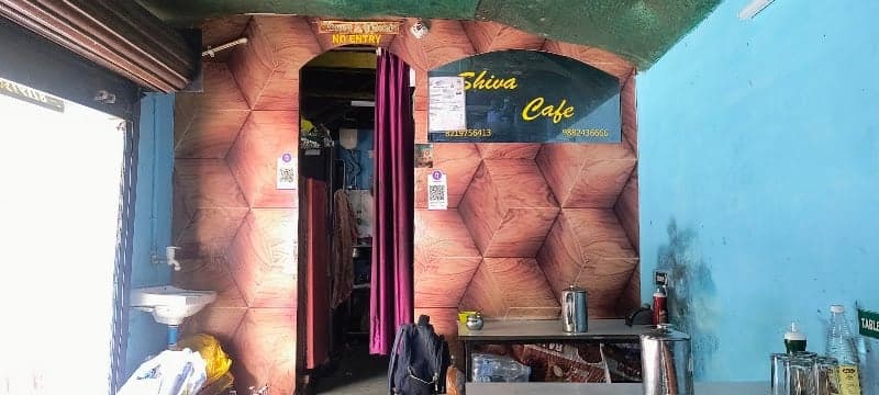 A cozy Shiva Cafe in Dharamshala, India, invites travelers with its vibrant blue walls, wooden textured panels, and inviting entrance, perfect for a relaxing coffee break amidst the scenic Himalayan backdrop.