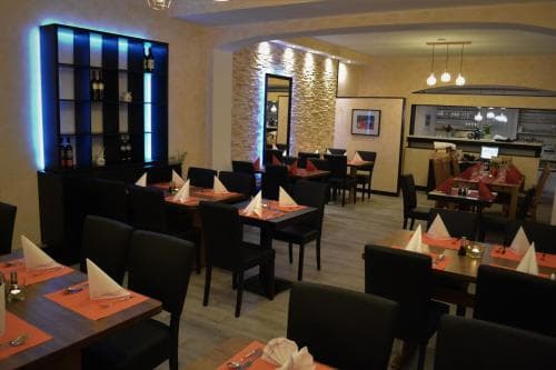 A cozy restaurant interior features warmly lit tables set with orange placemats and white napkins, creating an inviting atmosphere ideal for travelers seeking a comfortable dining experience.