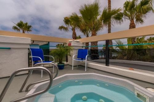 A serene rooftop hot tub area with palm trees and lounge chairs offers a relaxing retreat, ideal for travelers seeking a tranquil vacation spot.