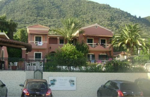 A serene coastal villa surrounded by lush greenery and palm trees offers a tranquil retreat, ideal for travelers seeking relaxation in a picturesque Mediterranean setting.