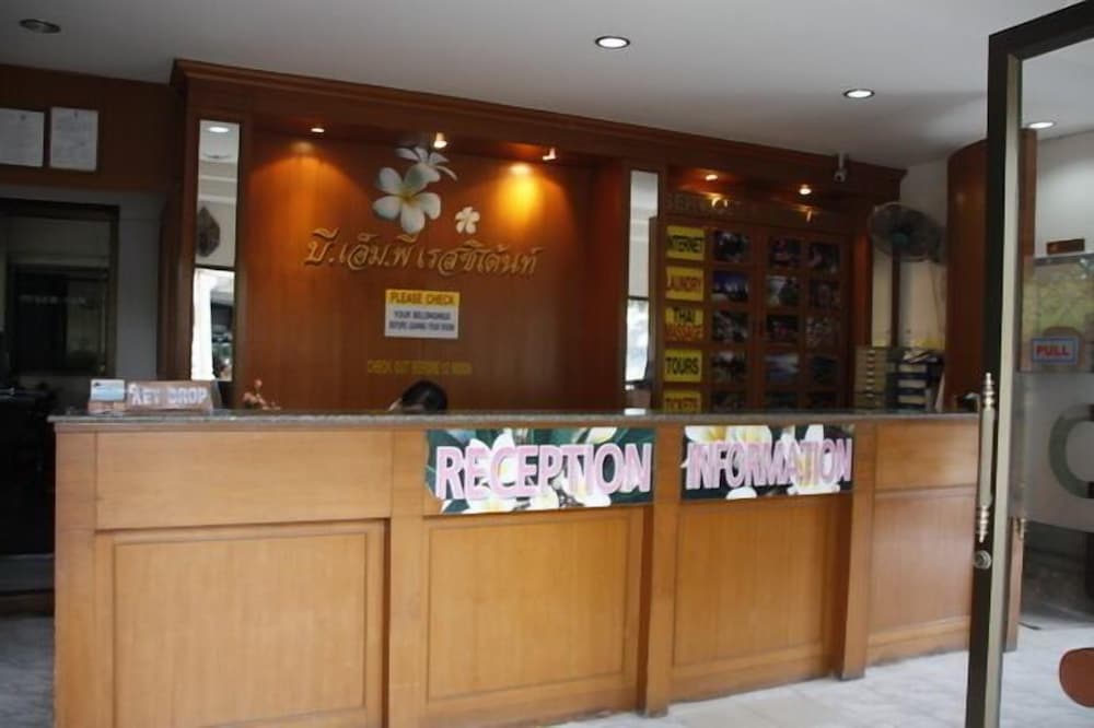 A warmly lit hotel reception area features wooden decor, floral accents, and service signs, creating an inviting atmosphere for travelers seeking information or assistance.