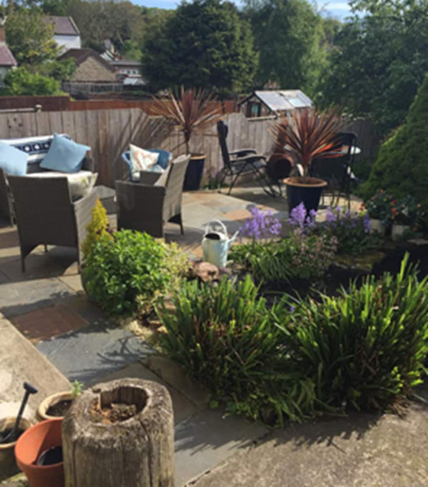 A serene suburban garden features comfortable seating, vibrant plants, and a cozy patio area, ideal for relaxing getaways or family retreats.