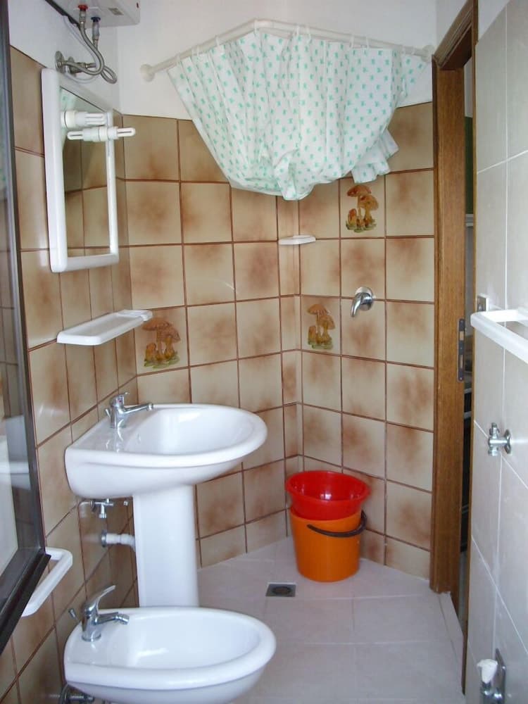 A cozy bathroom with earthy tiled walls, mushroom decals, and a red bucket adds charm to a traveler's accommodation, perfect for budget-friendly stays.