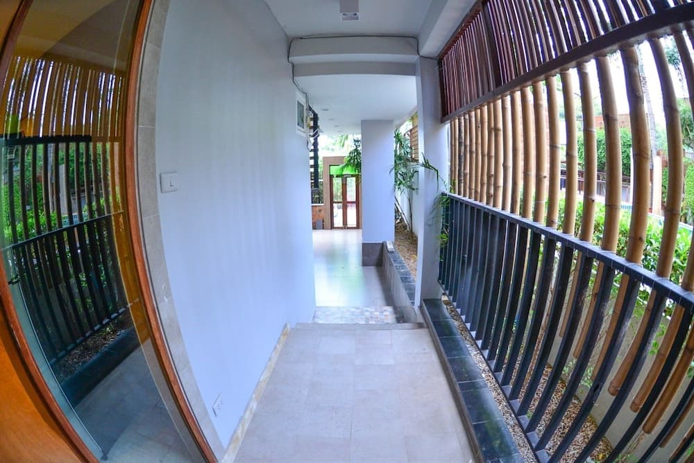 A serene hotel corridor with bamboo railings and lush greenery offers a tranquil atmosphere ideal for travelers seeking relaxation and privacy.