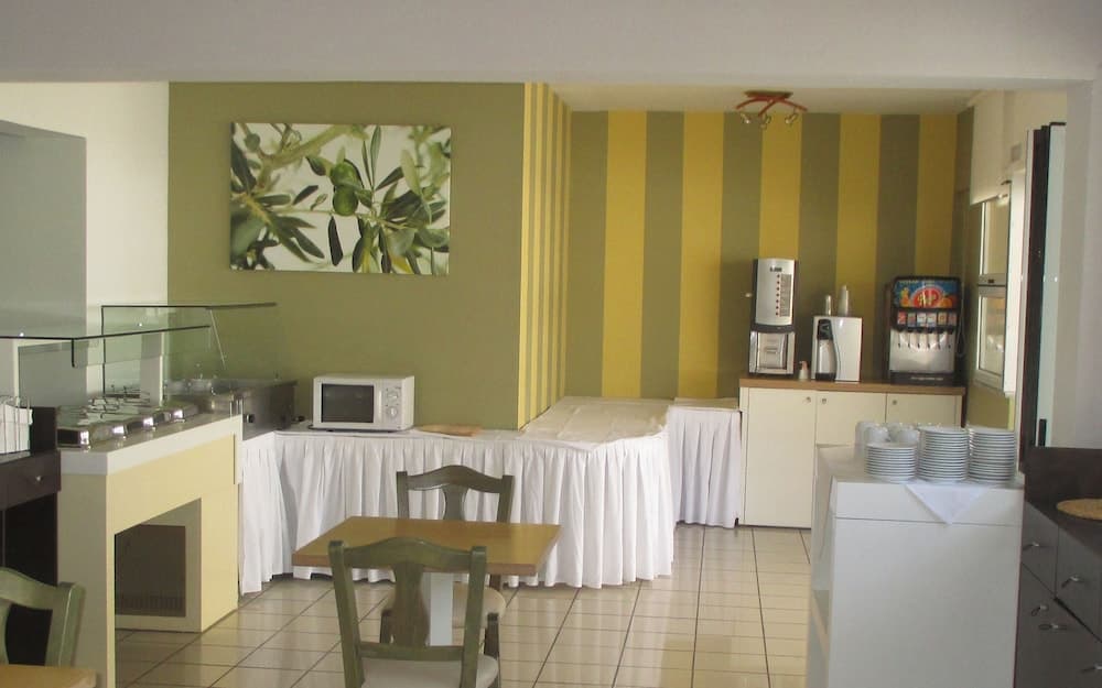 A cozy hotel breakfast area features striped yellow walls, white tablecloths, and a buffet setup, creating a welcoming atmosphere for travelers seeking convenience and comfort.