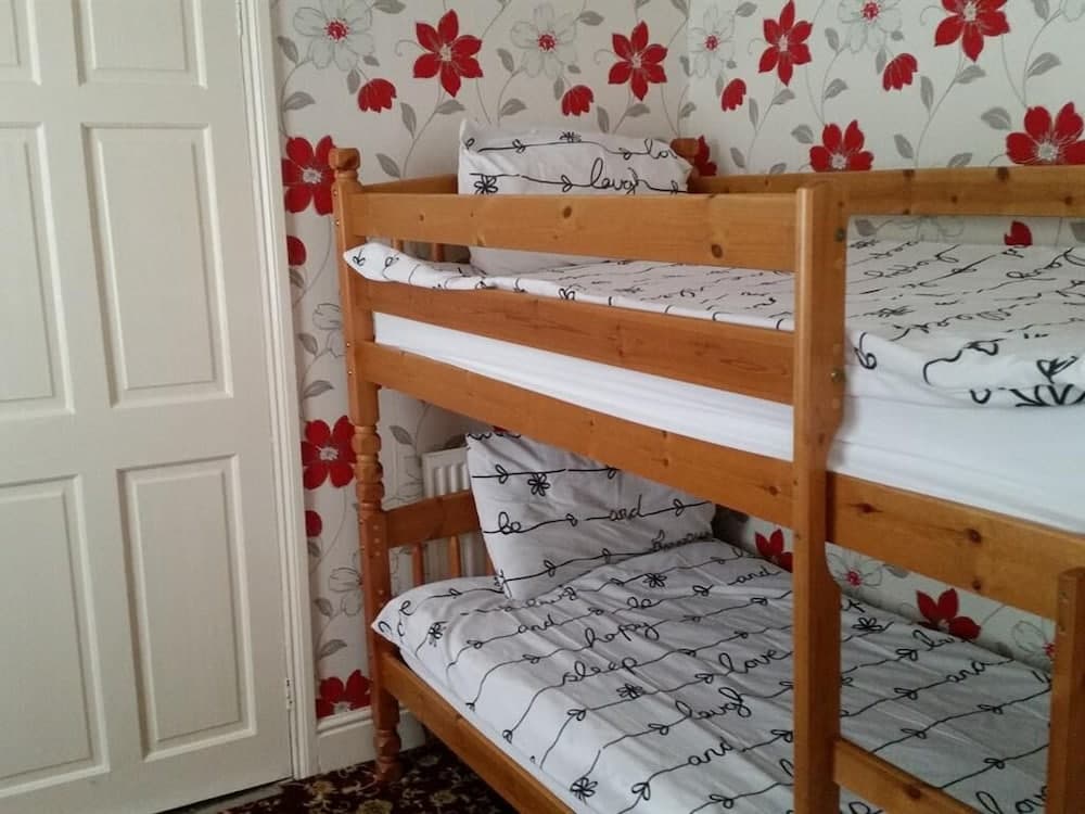 A cozy bedroom with floral wallpaper and wooden bunk beds adorned with patterned bedding invites travelers seeking comfortable family accommodations.