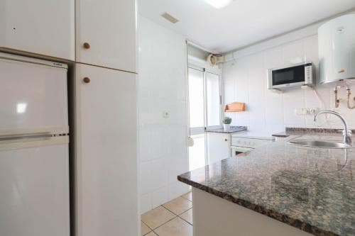 A bright, modern kitchen with white cabinetry, granite countertops, and stainless steel appliances creates a clean and inviting atmosphere, ideal for travelers seeking a cozy self-catering stay.