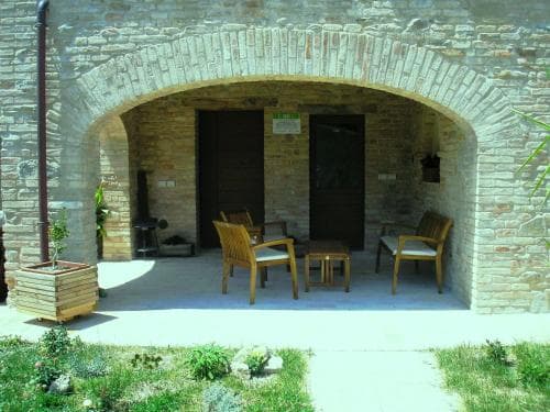 A serene outdoor seating area framed by an arched brick entrance invites travelers to relax in a rustic courtyard setting, perfect for a tranquil getaway.