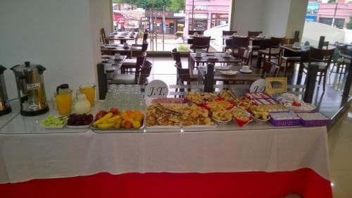 A vibrant buffet table laden with fresh fruits, pastries, and beverages invites travelers to enjoy a hearty breakfast in a cozy café setting, perfect for starting a day of exploration.