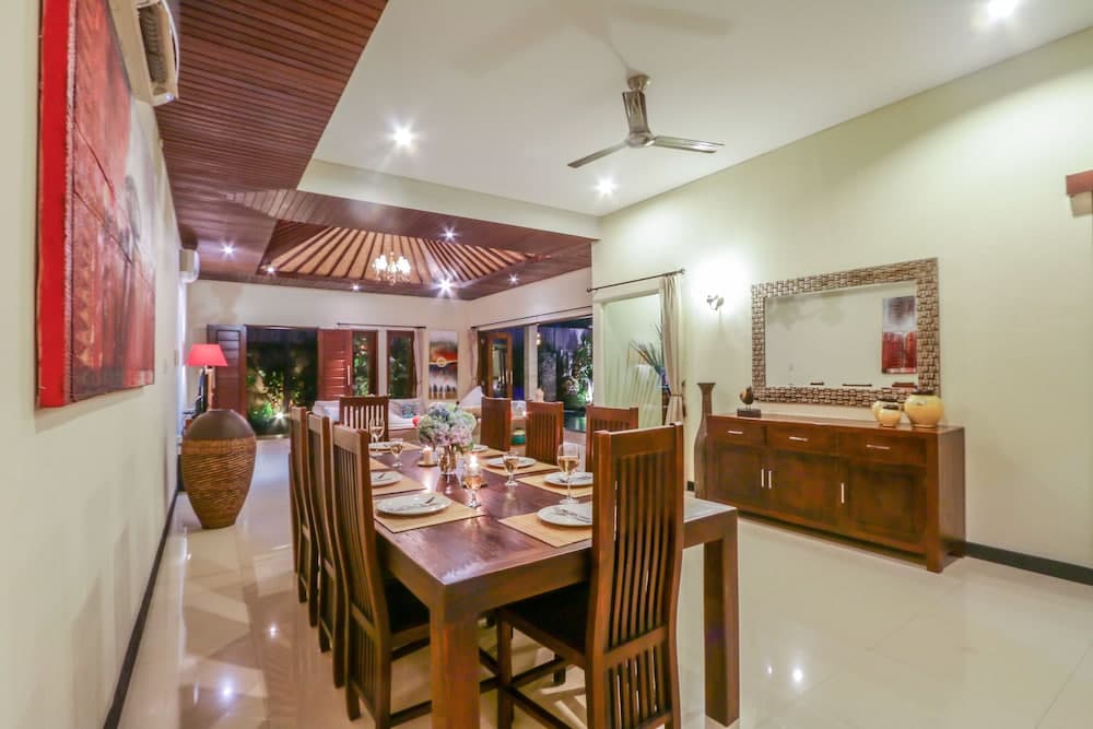 A cozy dining area with polished wooden furniture, warm lighting, and decorative accents creates an inviting atmosphere in a luxurious villa, perfect for travelers seeking comfort and elegance during their stay.