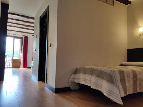 A cozy bedroom with wooden floors, striped bedding, and a balcony view invites travelers seeking a serene retreat in a modern apartment setting.