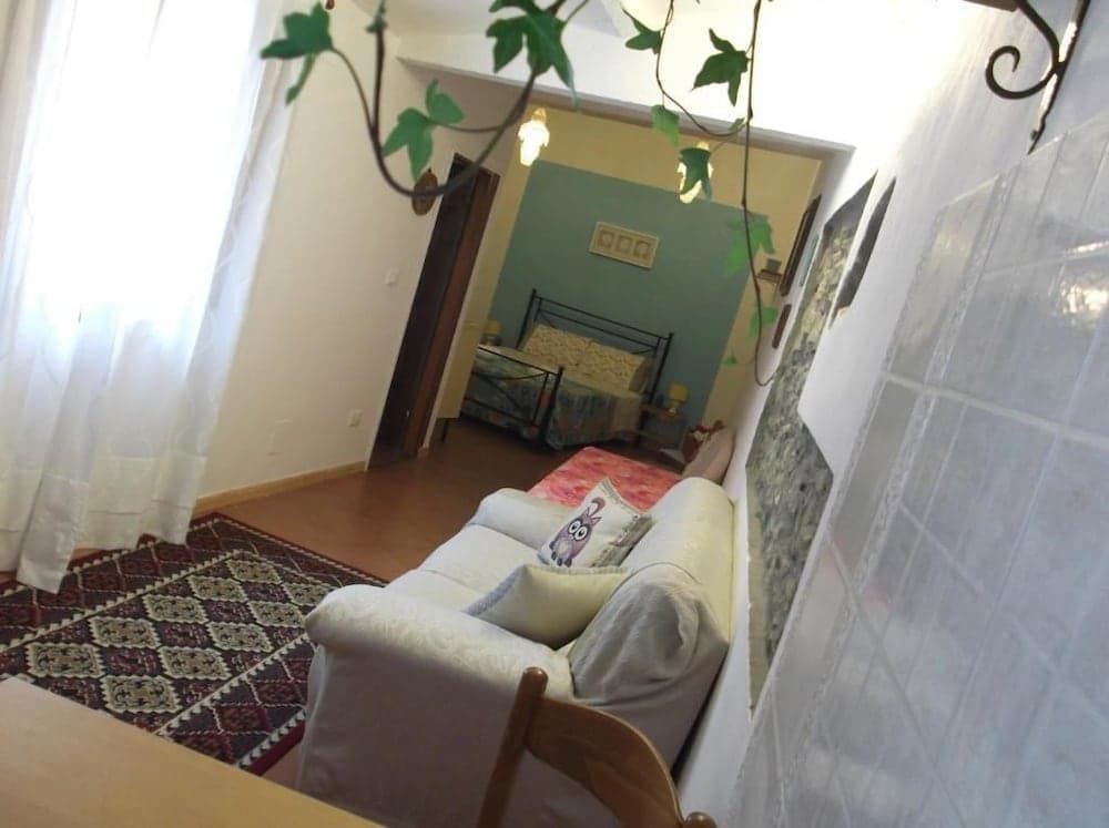 A cozy apartment interior features a white sofa adorned with playful pillows, a patterned rug, and a tiled wall, creating a warm and inviting atmosphere ideal for travelers seeking a comfortable stay.