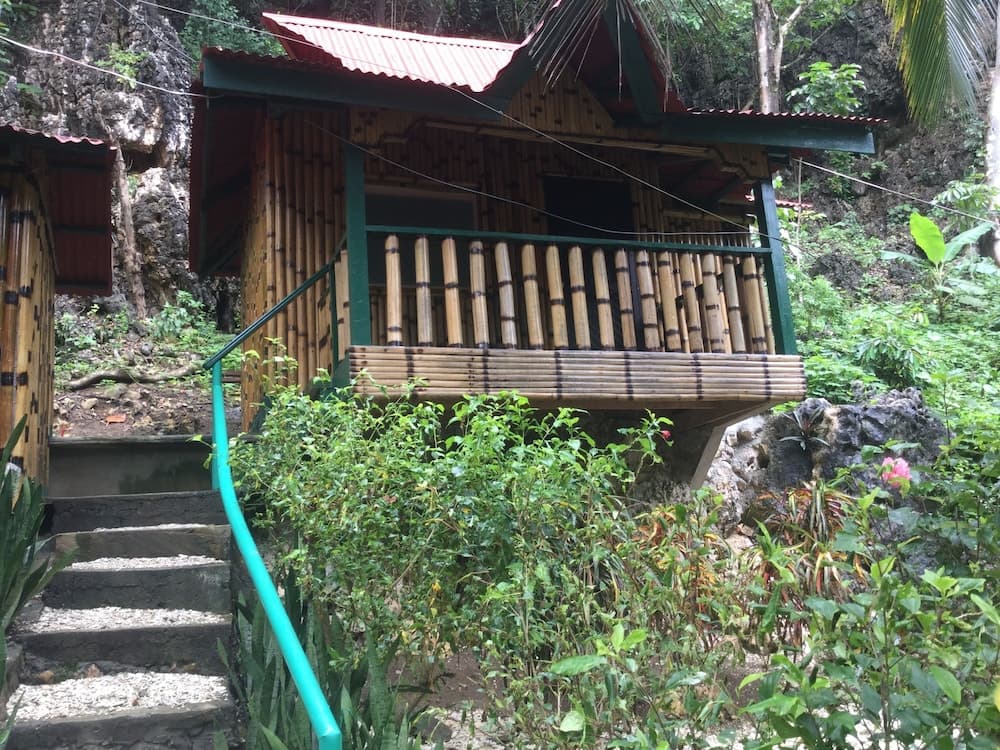 A serene bamboo cabin nestled in lush greenery offers a tranquil retreat, ideal for eco-tourists seeking a peaceful escape amidst nature.