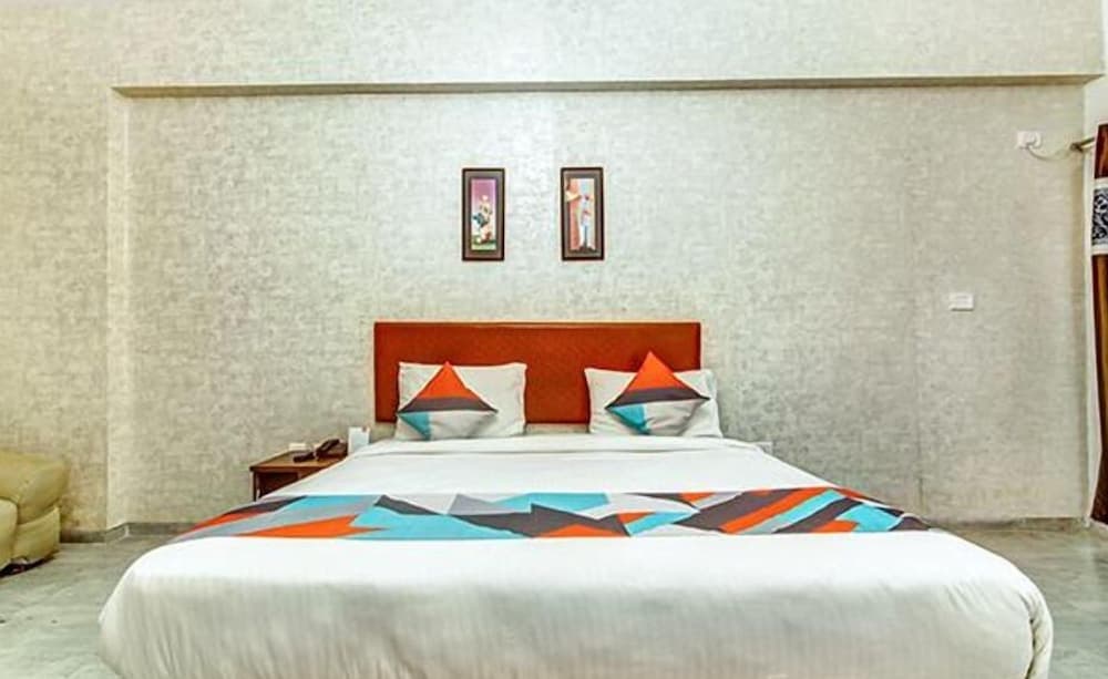 A cozy hotel room features a neatly made bed with vibrant geometric bedding, framed artwork on textured walls, and a minimalist aesthetic ideal for travelers seeking comfort and style.