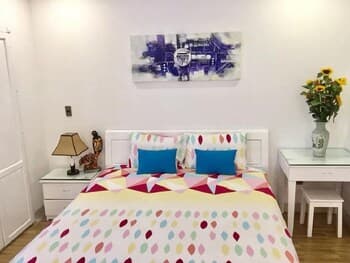A cozy bedroom with vibrant bedding, modern art on the wall, and sunflowers in a vase exudes warmth and comfort, ideal for travelers seeking a relaxing stay in a charming accommodation.
