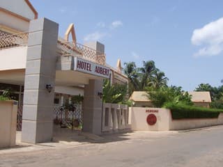 A welcoming entrance to Hotel Aubert features a modern archway, lush tropical greenery, and clear skies, ideal for travelers seeking a serene and inviting accommodation experience.