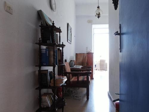 A cozy indoor hallway with a vintage bookshelf, wooden furniture, and a bright doorway leading to an outdoor patio, evokes a serene and inviting atmosphere perfect for a tranquil getaway or home stay experience.