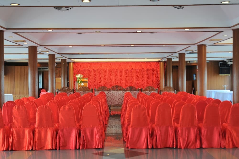 A spacious banquet hall adorned with vibrant red chairs and curtains exudes elegance, ideal for hosting grand events like weddings or conferences.