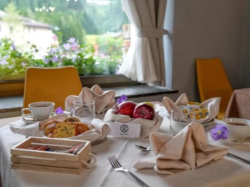 A cozy breakfast table set with fresh pastries, fruits, and flowers by a window overlooking a garden, perfect for a relaxing morning getaway in a charming hotel or bed-and-breakfast.