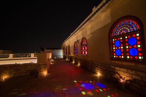 A serene rooftop terrace at night, illuminated by soft lights and vibrant stained glass windows, creates an enchanting atmosphere perfect for romantic getaways or cultural exploration.