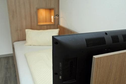 A cozy hotel room features a neatly made bed beside a sleek flat-screen TV, creating a modern and inviting atmosphere ideal for travelers seeking comfort and relaxation.