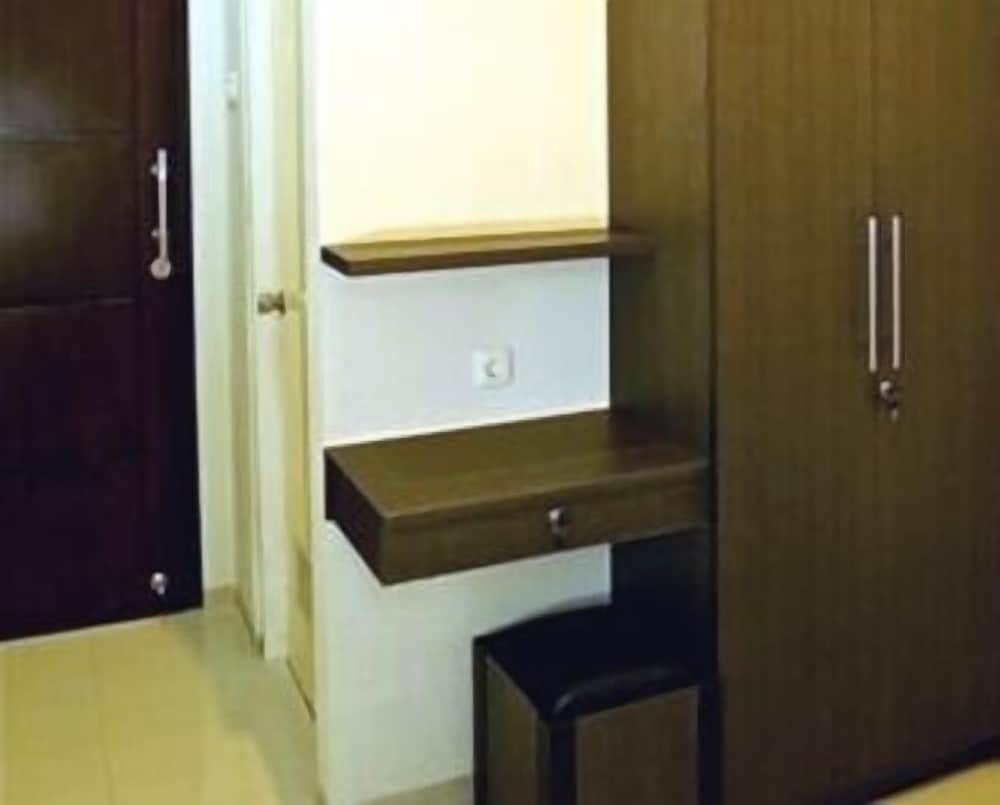 A cozy hotel room corner features a compact wooden desk with a drawer, a small shelf above it, and a sleek wardrobe, ideal for travelers seeking functional yet minimalist accommodations.