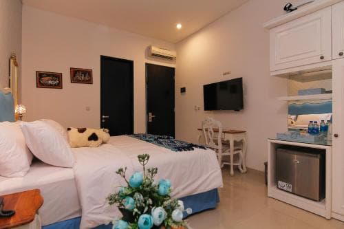 A cozy hotel room features a neatly made bed adorned with a plush pillow, a small dining area, and a compact kitchenette, creating a welcoming atmosphere ideal for travelers seeking comfort and convenience.