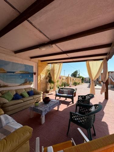 A cozy outdoor patio with comfortable seating, vibrant curtains, and a scenic mural invites travelers to relax in a warm, inviting atmosphere perfect for leisurely getaways.
