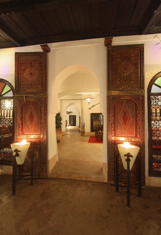 A warmly lit, ornate hallway with intricate wooden panels and archways evokes a serene, traditional ambiance ideal for cultural exploration and heritage tourism.