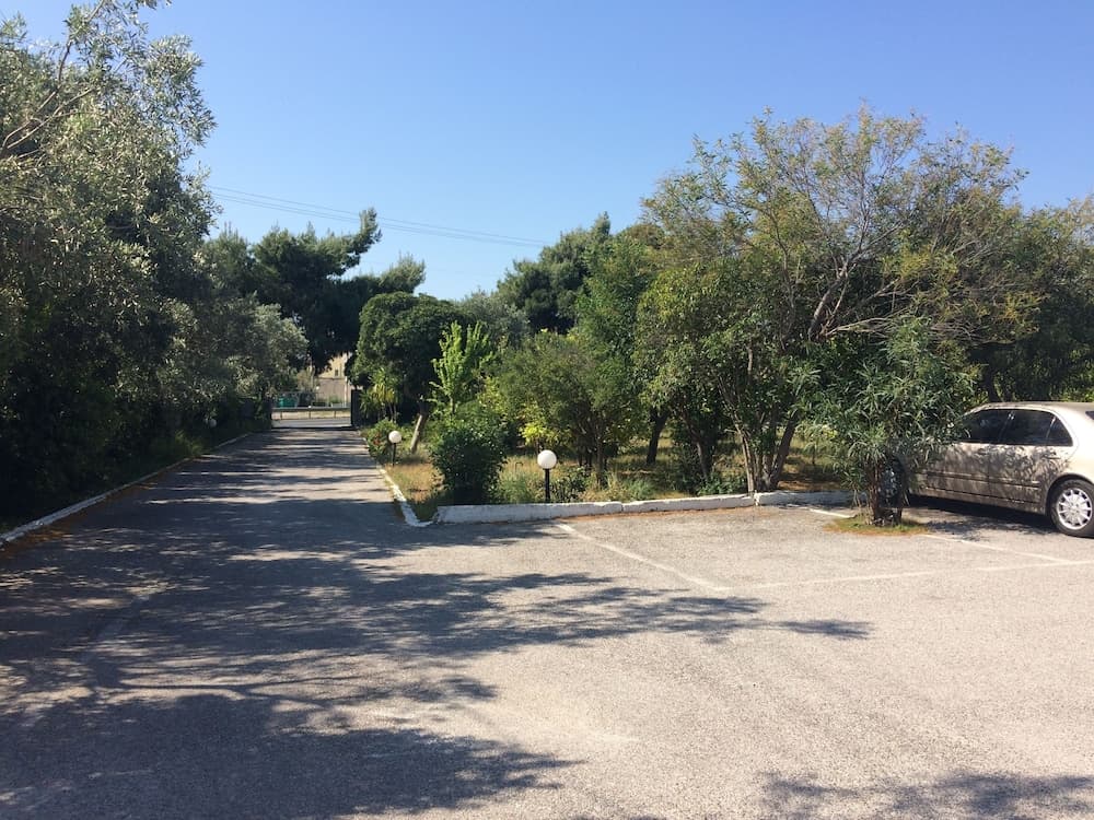 A serene rural road lined with lush greenery and lampposts under a clear blue sky, ideal for a peaceful countryside getaway.