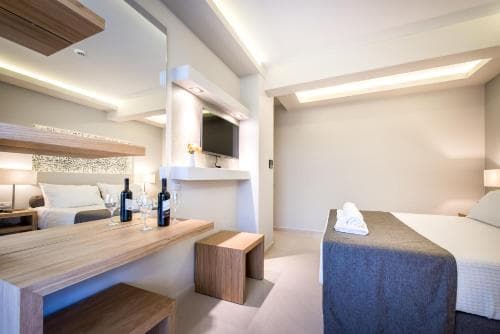 A modern hotel room features a cozy bed, sleek wooden furniture, and ambient lighting, creating a serene atmosphere ideal for travelers seeking comfort and relaxation.