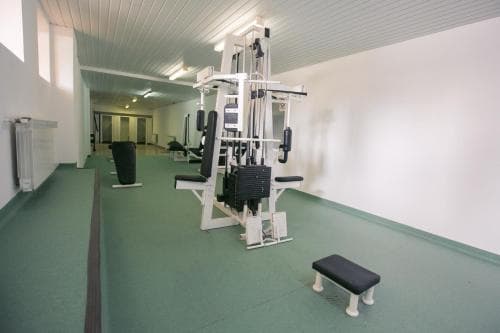 A well-lit indoor fitness center features modern exercise machines on green flooring, ideal for travelers seeking a workout-friendly accommodation option.