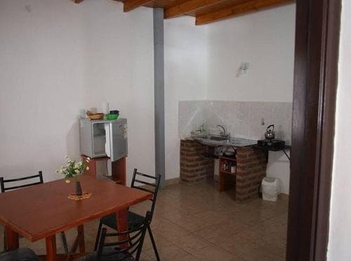 A cozy, rustic kitchenette with tiled floors, brick accents, and simple furnishings creates an inviting atmosphere ideal for travelers seeking a quaint, self-catering accommodation experience.