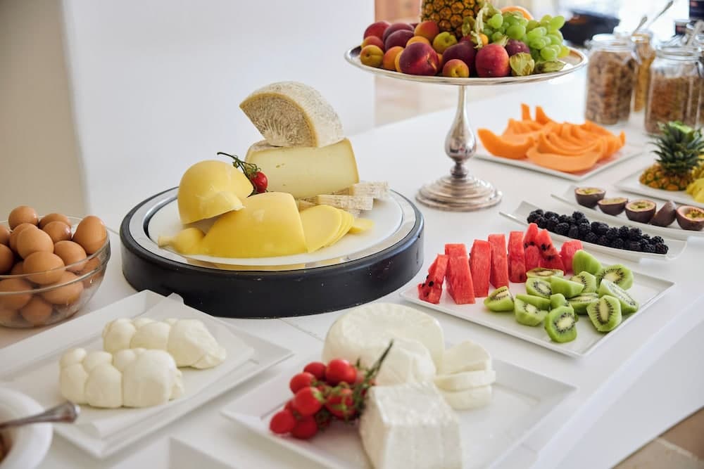 A vibrant breakfast buffet table displays an array of fresh fruits, cheeses, eggs, and spreads, creating an inviting and colorful scene perfect for a luxurious hotel stay or resort experience.