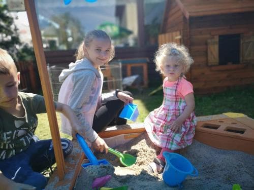 Children enjoy playful moments in a sunny backyard sandbox filled with colorful toys, ideal for family-friendly outdoor activities and capturing joyful childhood memories.