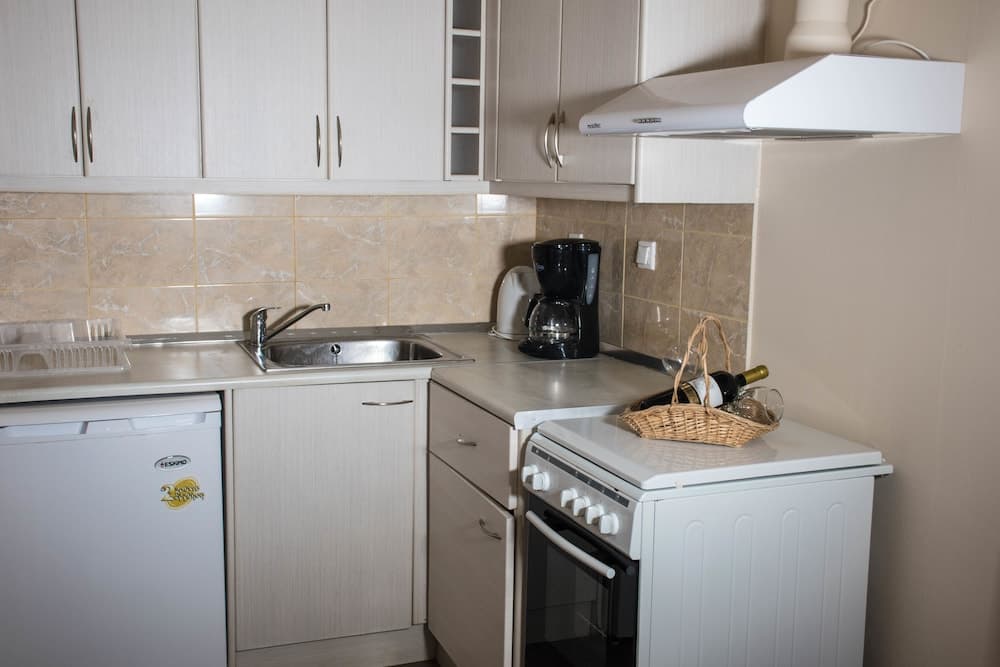 A cozy, compact kitchenette featuring white cabinetry, a tiled backsplash, and essential appliances like a stove and coffee maker, ideal for travelers seeking self-catering accommodations.
