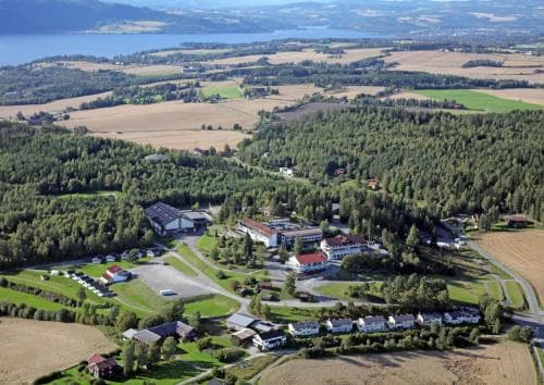 An aerial view captures a serene rural landscape with scattered houses, lush greenery, and distant lakes, ideal for tranquil countryside retreats and nature exploration.