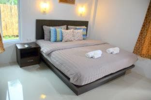 A cozy bedroom with a neatly made bed, soft lighting, and vibrant textiles creates a serene atmosphere ideal for travelers seeking relaxation in a private retreat.