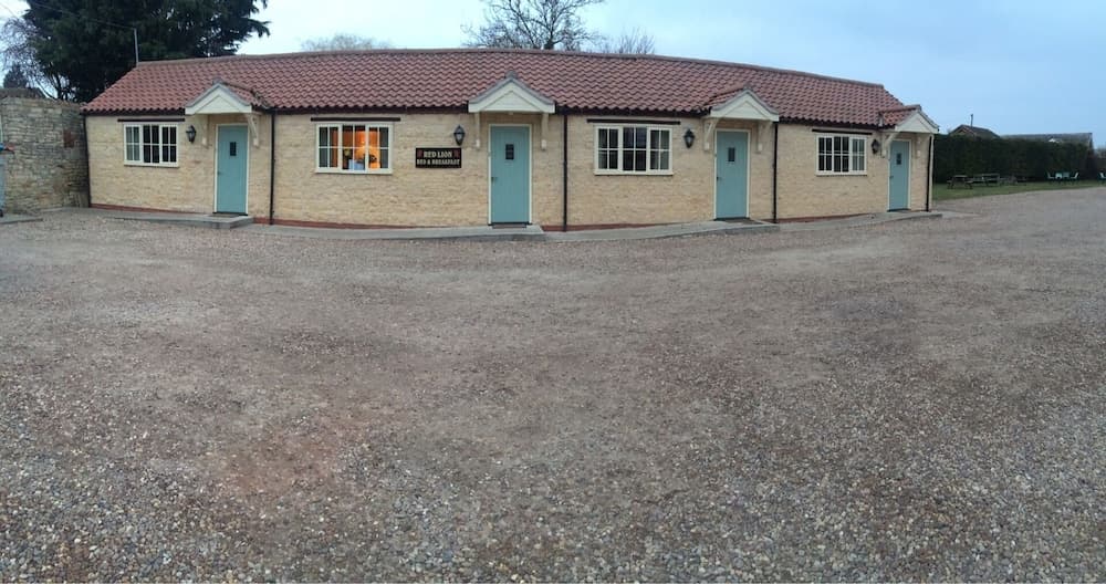 A quaint countryside bed and breakfast with charming brick architecture, pastel doors, and a gravel courtyard invites travelers seeking a peaceful rural retreat.