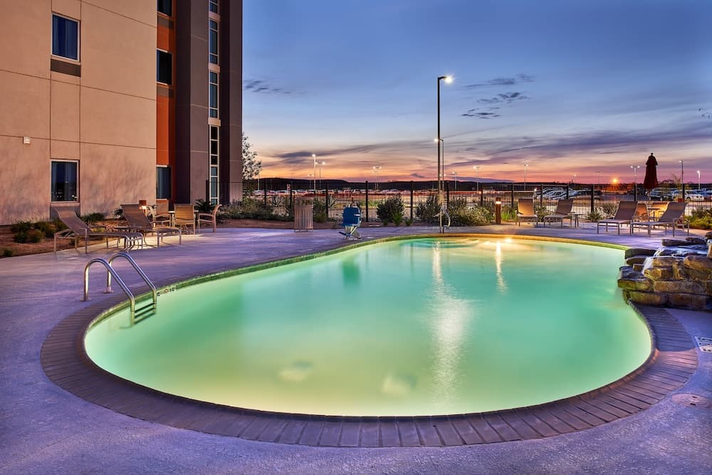 A serene evening at an outdoor hotel pool area features glowing water, lounge chairs, and a twilight sky, ideal for relaxation and leisure travel photography.