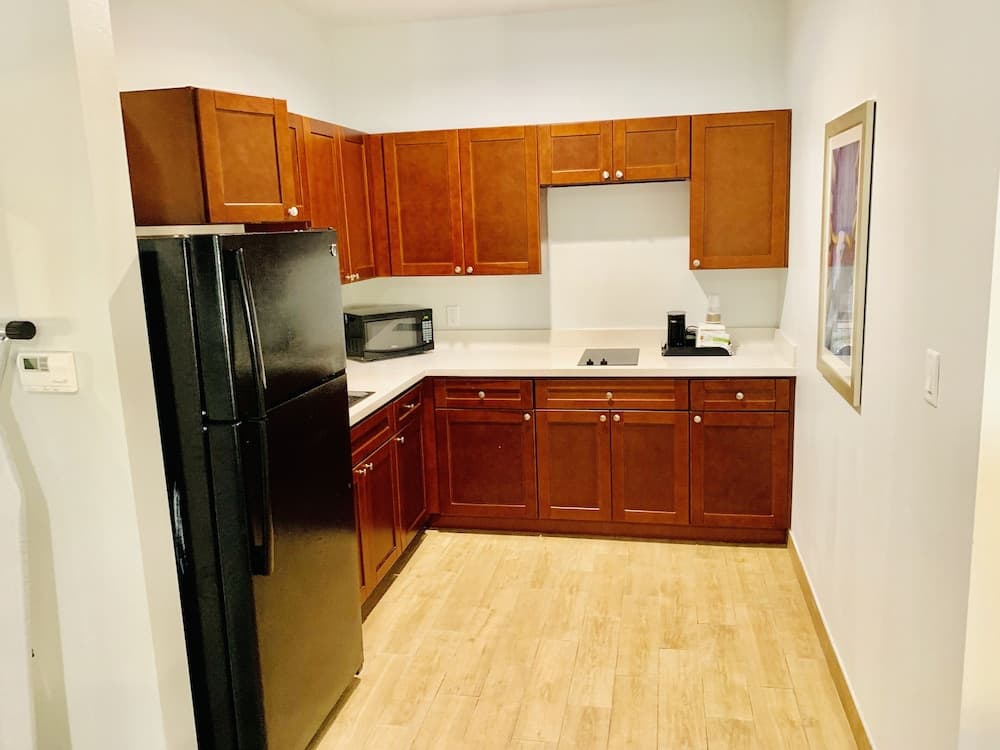 A cozy apartment kitchen features warm wooden cabinets, black appliances, and a light wood floor, ideal for travelers seeking a homey cooking experience during their stay.