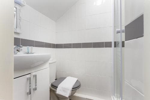 A clean, modern bathroom with white tiles, a sleek sink cabinet, and a glass shower enclosure offers a refreshing space for travelers seeking comfort and hygiene during their stay.