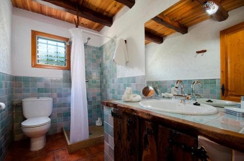 A cozy rustic bathroom with wooden beams, tiled walls, and a wooden vanity exudes warmth and charm, ideal for travelers seeking a quaint and inviting accommodation experience.