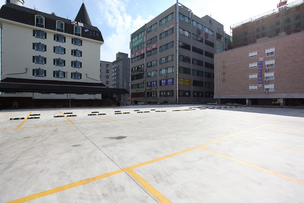 An empty urban parking lot surrounded by modern buildings under a partly cloudy sky offers a practical space for travelers seeking convenient city access.