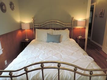 A cozy bedroom with a neatly made bed, warm lighting from bedside lamps, wooden flooring, and a serene ambiance, ideal for travelers seeking a peaceful retreat.