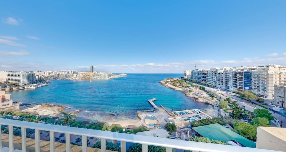 A serene coastal cityscape with turquoise waters, modern buildings, and lush greenery under a clear blue sky, ideal for travelers seeking a relaxing seaside retreat.