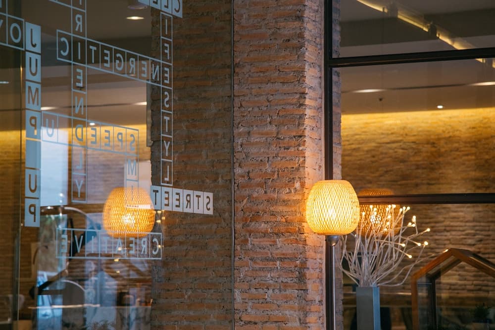 A cozy indoor space with exposed brick walls, warm lighting from spherical lamps, and glass panels adorned with motivational words, ideal for travelers seeking a creative and energetic atmosphere in a modern café or lounge.