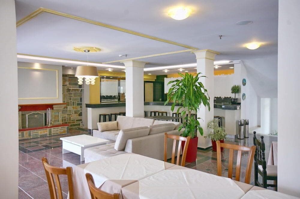 A cozy hotel lobby features comfortable seating, potted plants, and a warm ambiance, ideal for travelers seeking relaxation and hospitality.